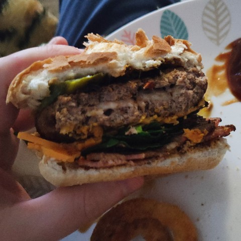 The same beef burger roughly cut in half, showing the white mozarella cheese in the center