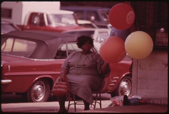 “Black woman selling gas filled “have a happy day” balloons on a Chicago South Side street…”  (1973–4) by John H. White, from Documerica.
Source: U.S. National Archives