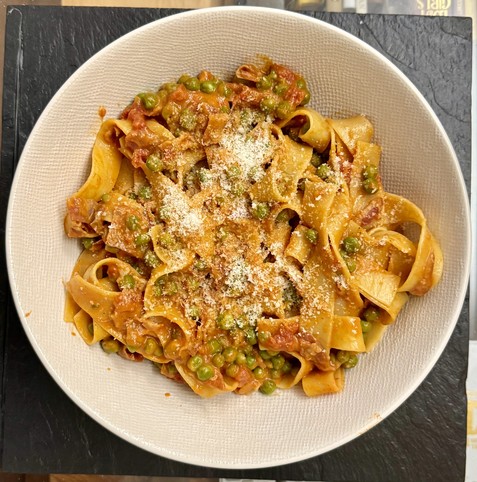 Papardelle (wide pasta) in a sauce made with pancetta, tomatoes, peas and a hint of heavy cream; some grated Parmesan on top