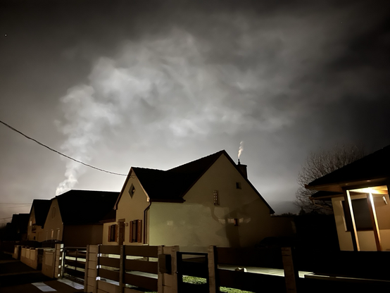 Houses in the evening in Hungarian village; backlight from a lit-up playfield.