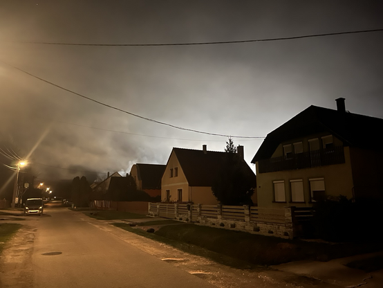 Houses in the evening in Hungarian village; backlight from a lit-up playfield.