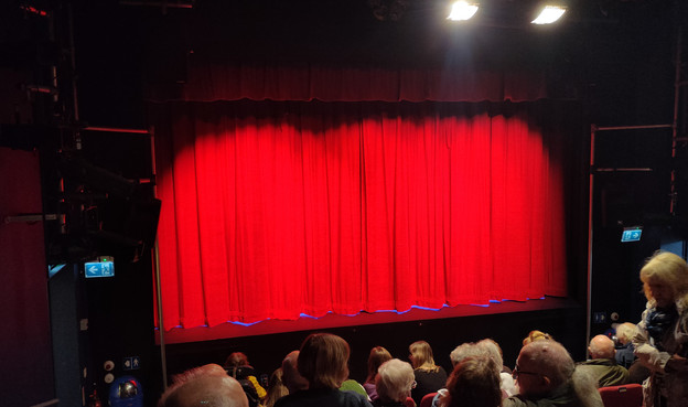 A theatre stage covered by red curtains.