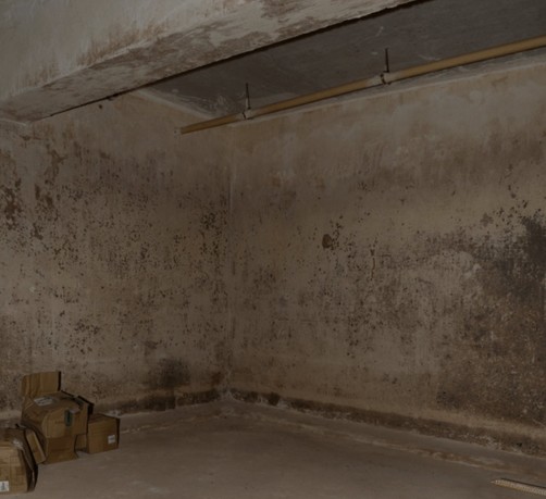 epstein files dim dirty concrete corner room with boxes and pipe
