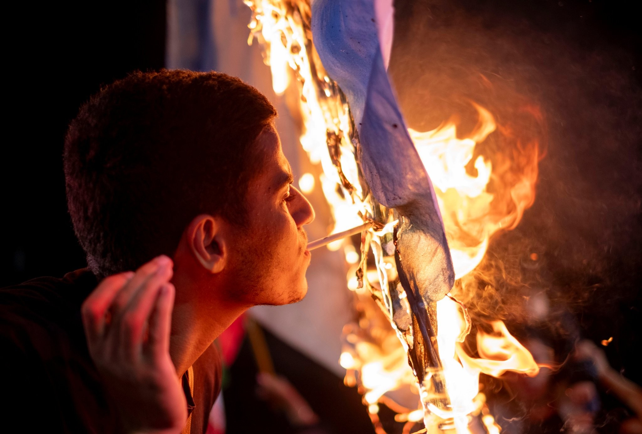 Iranian man lighting blunt on burning Israeli flag