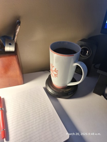 Large mug of coffee on home office desk. Hardcover notebook ready.