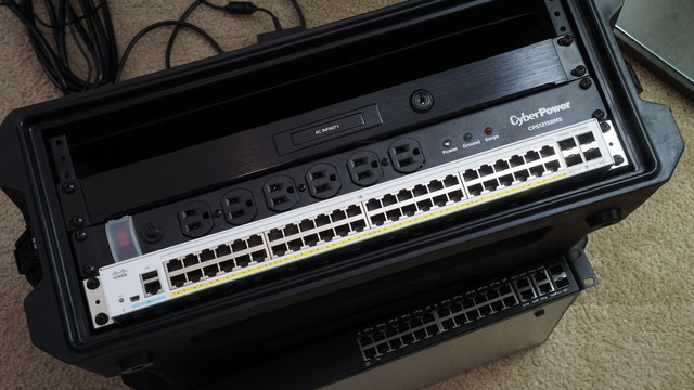 The Cisco Catalyst 1000 switch installed in the portable case underneath the PDU and rack drawer.