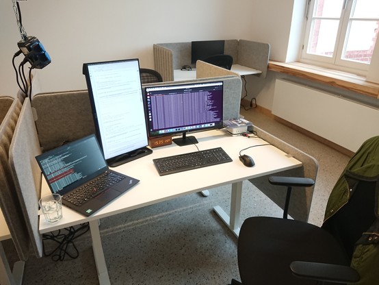 Desk with two screens connected to a Mac Mini, with a laptop next to them. 