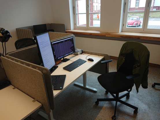 Desk with two screens connected to a Mac Mini, with a laptop next to them. 