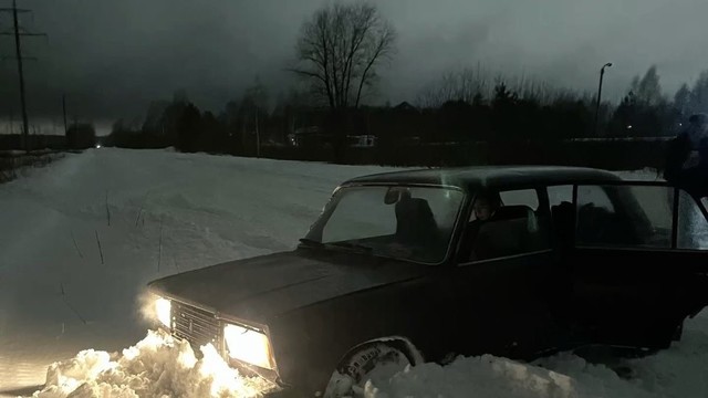 car buried in snowy road, headlights glow the mount in front