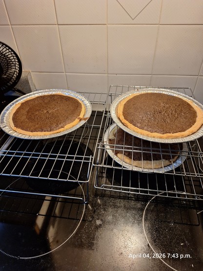 Three chocolate pies on racks cooling.