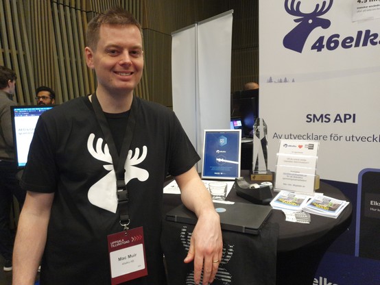 Mac Muir from 46elks in front of their booth at Uppsala tillväxtdag, featuring Update flyers.