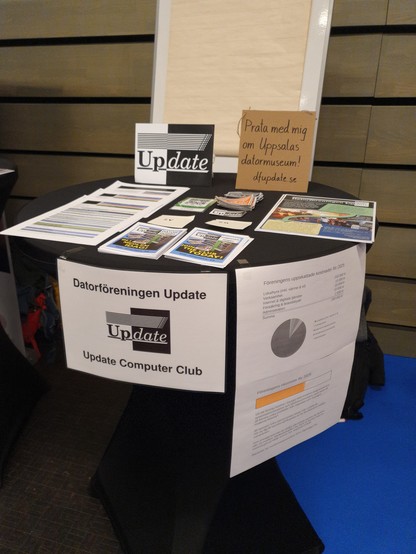 Update's booth at Uppsala tillväxtdag with flyers, newsletters, and merch.