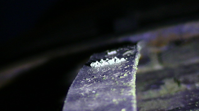 a thick ribbon of lightning conductor cable dodah on the side of a blue brick structure in torchlight. there is lichen