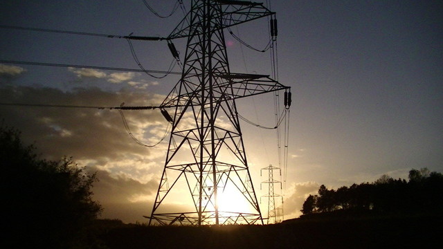 electricity pylons in front of the setting sun from further back. there is a bit more of the first pylon in shot
