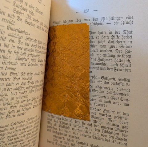 An open book with a small orange chocolate wrapping inside.