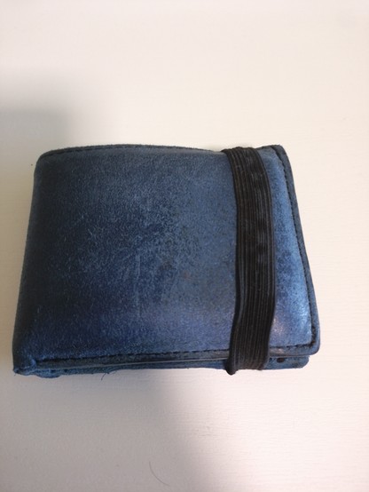 La misma cartera azul cerrada con una goma elástica negra que sirve para evitar que se abra accidentalmente