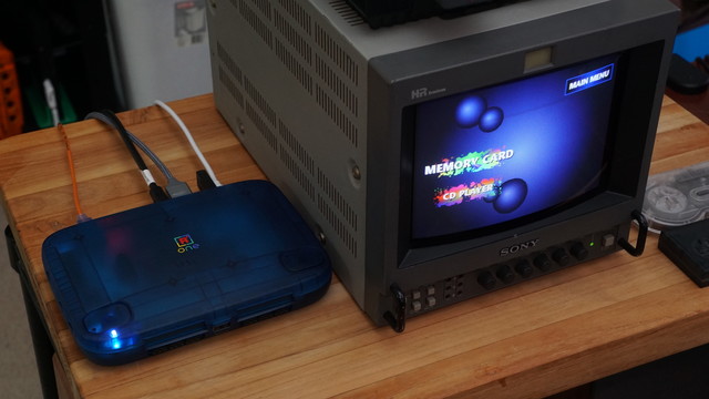 A picture of a blue Superstation One connected via RGB to a Sony PVM-9044Q television.  The screen shows the "Memory Card" and "CD Player" options.