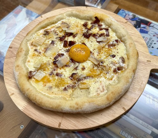 A pizza with a heavy cream base, then mozzarella, then chorizo cut in small dices. After cooking an egg yolk is placed in the center, then some Parmesan and red Kampot pepper.