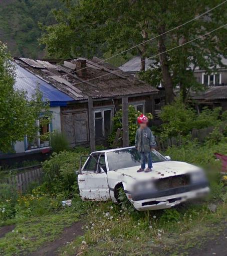 blurred out google street view kid standing atop beat up car with wild greenery photo by nich morgenbach