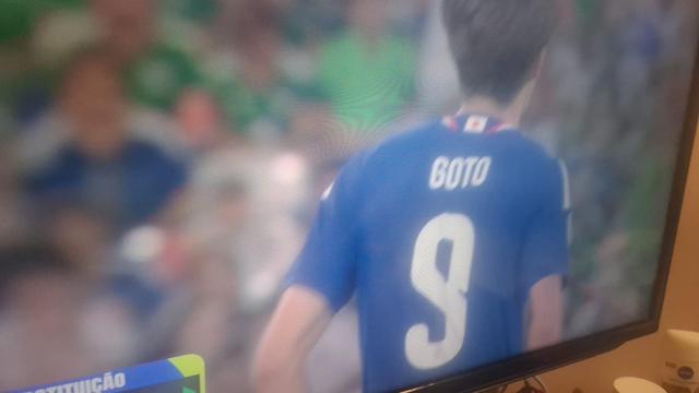 Foto de uma TV mostrando um jogador de futebol usando camisa azul na qual lemos o seu nome: GOTO.