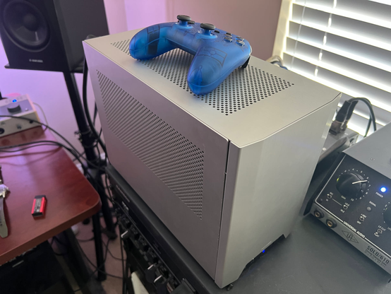 The knock-off Steam Machine living in a silver NCASE M1 V5.0 case.  Not too big, definitely an mITX build.  On top of the silver case is a blue PS1 controller for scale.