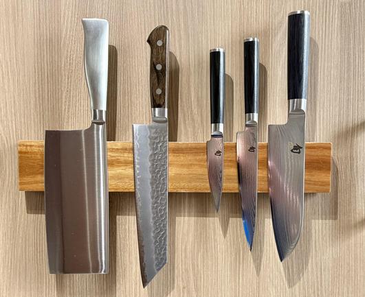 The same stored on a magnetic bar next to its new family, three Shun knives and a big stainless steel chopping knife