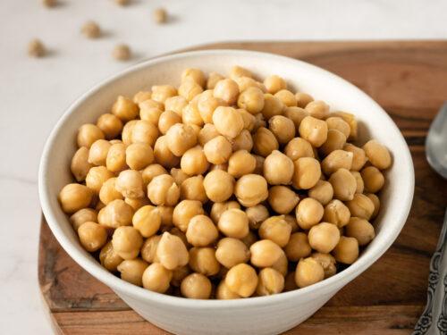 Chickpeas in a white bowl on a wooden table.