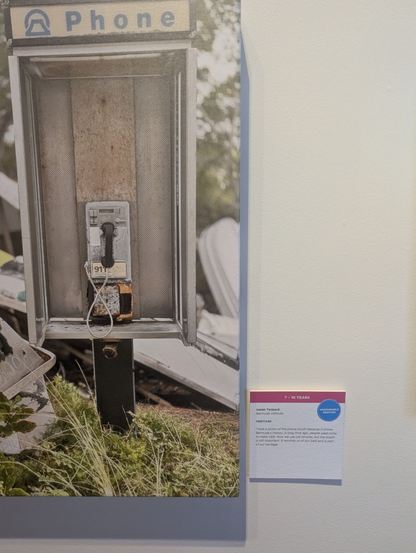 Payphone photo in the National Museum of Bermuda,  as taken by a 7-10 year old. The description includes the phrase "A long time ago, people used coins to make calls."