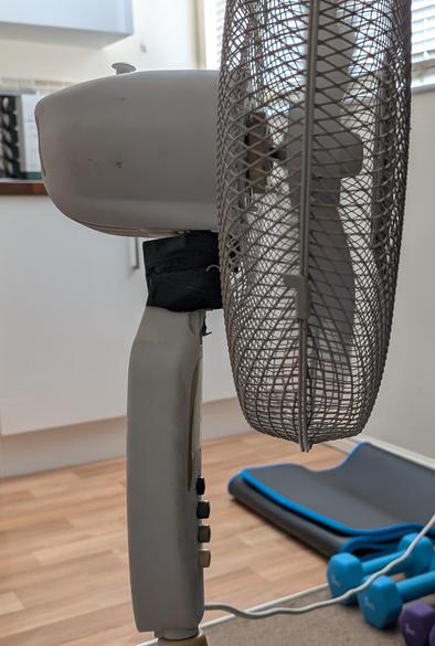 The business end of a 40cm (16in) standing fan. It has 4 buttons: off, slow, medium, fast. The tilt action is held together with black duct tape.