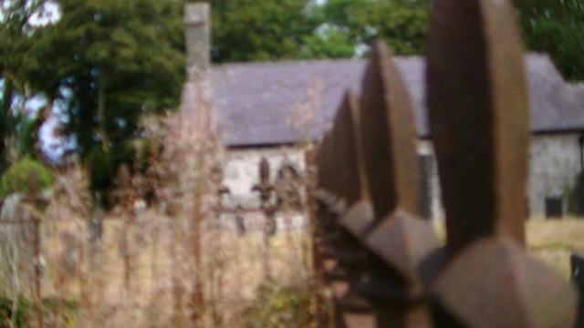 looking along blurry rusty railings, at a blurry church in a blurry dry graveyard. 