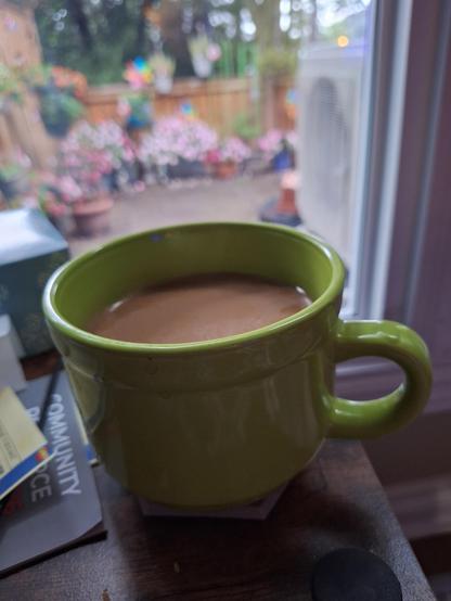 Large green coffee mug filled with coffee and a shot of cream.