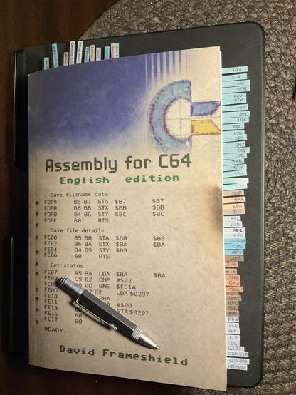 The book Assembly for C64 with around 60 little colored index markers with handwriting on them. 