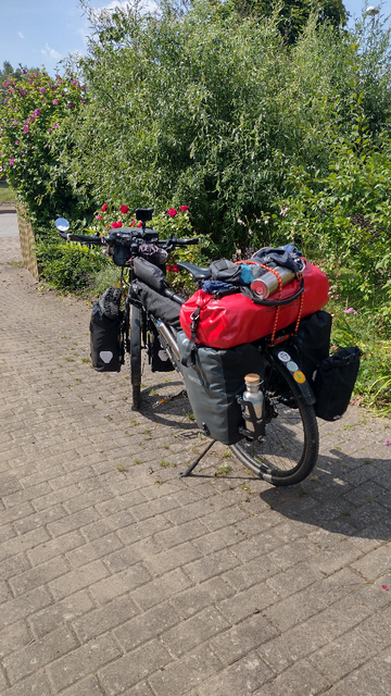 Reiserad, fertig gepackt mit dunkelgrauen Packtaschen vorn und hinten je eine rechts und eine links, zusätzlich eine rote Tasche auf dem Gepäckträger.