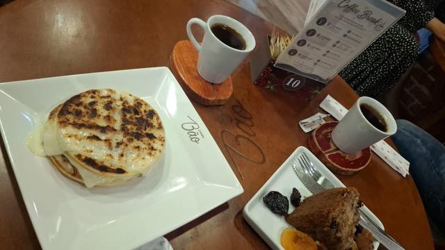 Fornecido por @altbot, gerado localmente e de forma privada usando Gemma4:26b e posteriormente editado pelo autor do toot.

Uma foto de ângulo superior mostra uma mesa de madeira com pratos e xícaras xícaras de café. À esquerda, um prato quadrado branco contém uma massa circular espessa e tostada com queijo derretido na borda e o logotipo "Trem Bão". Duas xícaras brancas com café preto estão sobre a mesa em descansos individuais. Vemos um menu de pé, próximo a um pequeno prato com bolo, frutas …