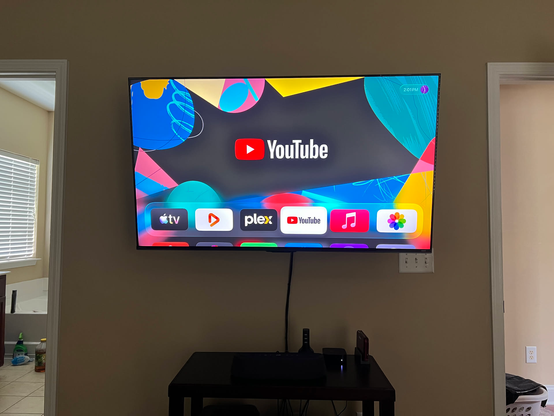A working 55" flat-screen TV mounted to the wall above a soundbar.