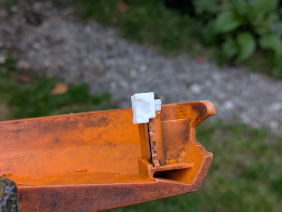 a half-eroded bit of 3D-printed PLA clamping a blade onto a strimmer deck