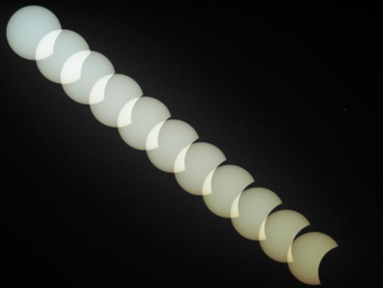 eine Reihe von Sonnenscheibchen von links oben nach rechts unten diagonal durch das schwarze Bild. 