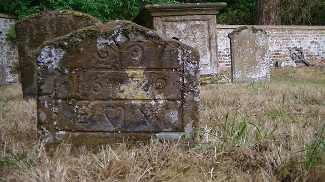 another iron stone looking grave partially covered in moss and lichen.
"1670
E  ♡ W"
