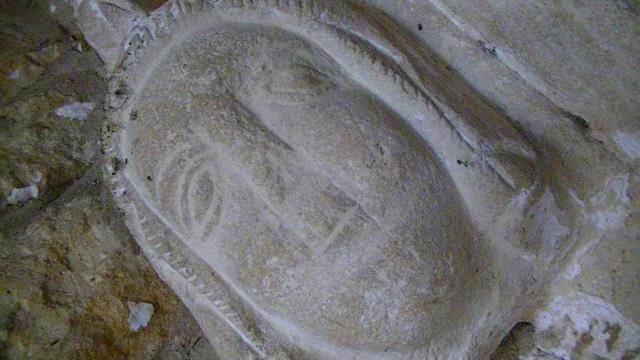 an old church doorway hoodmould label stop carving of a persons head, in a pale limestone. the doorway is inside an old porch so this is even older than the porch.
the church dates back to the 13th century.