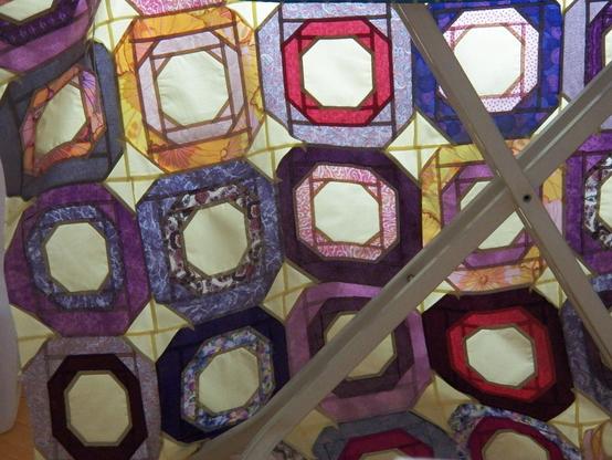 Ein zusammengenähtes durchscheinendes Patchwork-Stoffteil, man sieht die Säume weil der Stoff sehr dünn ist und von hinten beleuchtet wird. Es hat damit eine Wirkung wie ein Bleiglas-Kirchenfenster. 