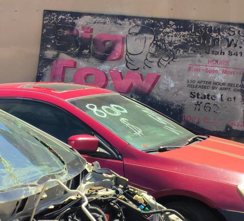 big tow with a toe logo lot with a red car and exposed trunk