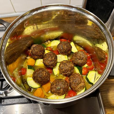 Onion, carrots, zucchini, chickpeas and cherry tomatoes simmering in the stock. On top eight meatballs made with merguez stuffing