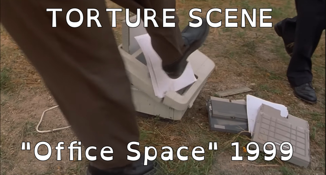 A frame from the movie "Office Space" where some IT guys are kicking and beating (with baseball bats) an office printer in a field to let out their frustration.

The text on top of image says "torture scene" in caps.
At the bottom is written '"Office Space" 1999'.