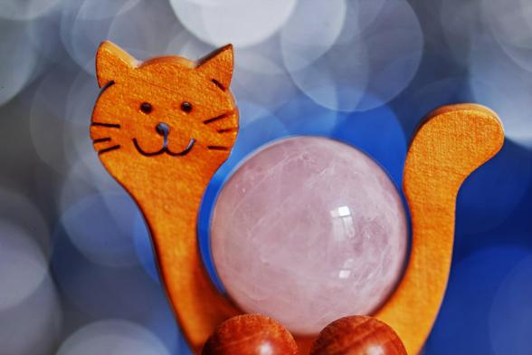 Eine kleine Deko in Form einer lächelnden Katze aus Holz und Stein. Der Rumpf der Katze ist eine Kugel aus poliertem Rosenquarz, auch die Füsse der Katze wurden durch kleine Kugeln aus Holz ersetzt, also eine Katze auf Rädern.