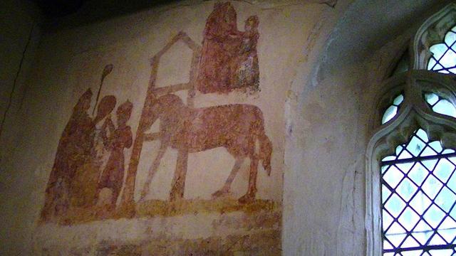a rusty colour wall painting of some religious figures an a horse. on the left one of the figures is holding something round and maybe a staff, like a bishop or something. figures on top right maybe a mother and child. part of a leaded church window visible on the right.
I just searched it up -> "The St Eligius picture. Eligius is the patron saint of goldsmiths and silversmiths "
