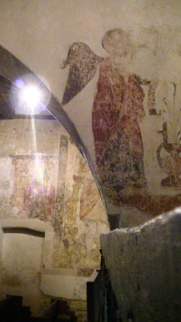 a painting of an angel. these paintings are very faded and a bit flakey. they were slapped on about 600 years ago and not been touched since. anyway the angel is on an arch and there is part of another painting of st.Christopher on the wall behind.