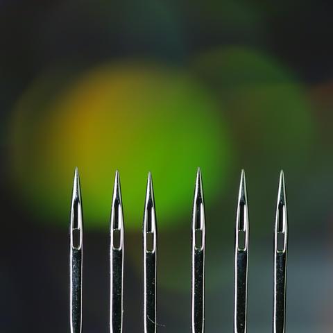 Nahaufnahme von den Spitzen von sechs Nadeln für die Nähmaschine. Die Nadeln kommen von unten senkrecht ins Bild die Spitzen zeigen nach oben.